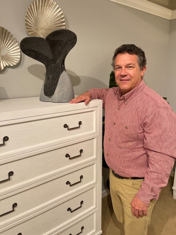 American Woodcrafters CEO Charles Foster is an accomplished sculptor who brings an artist's eye to designing furniture collections. He's shown here with one of his tabletop sculptors on a chest in the AWC bedroom line.